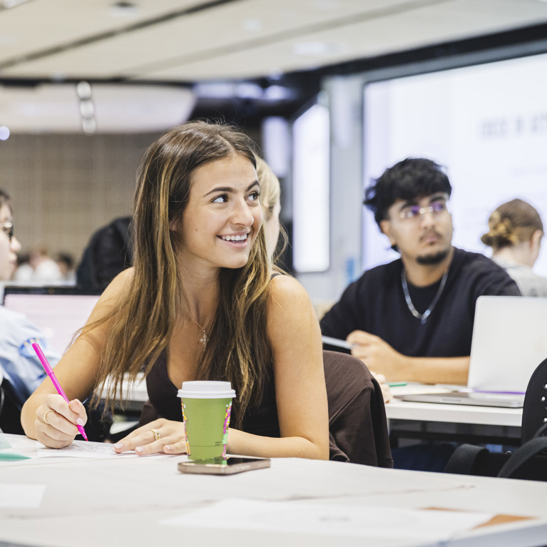 University of Technology Sydney students smiling while sitting at desks in a seminar