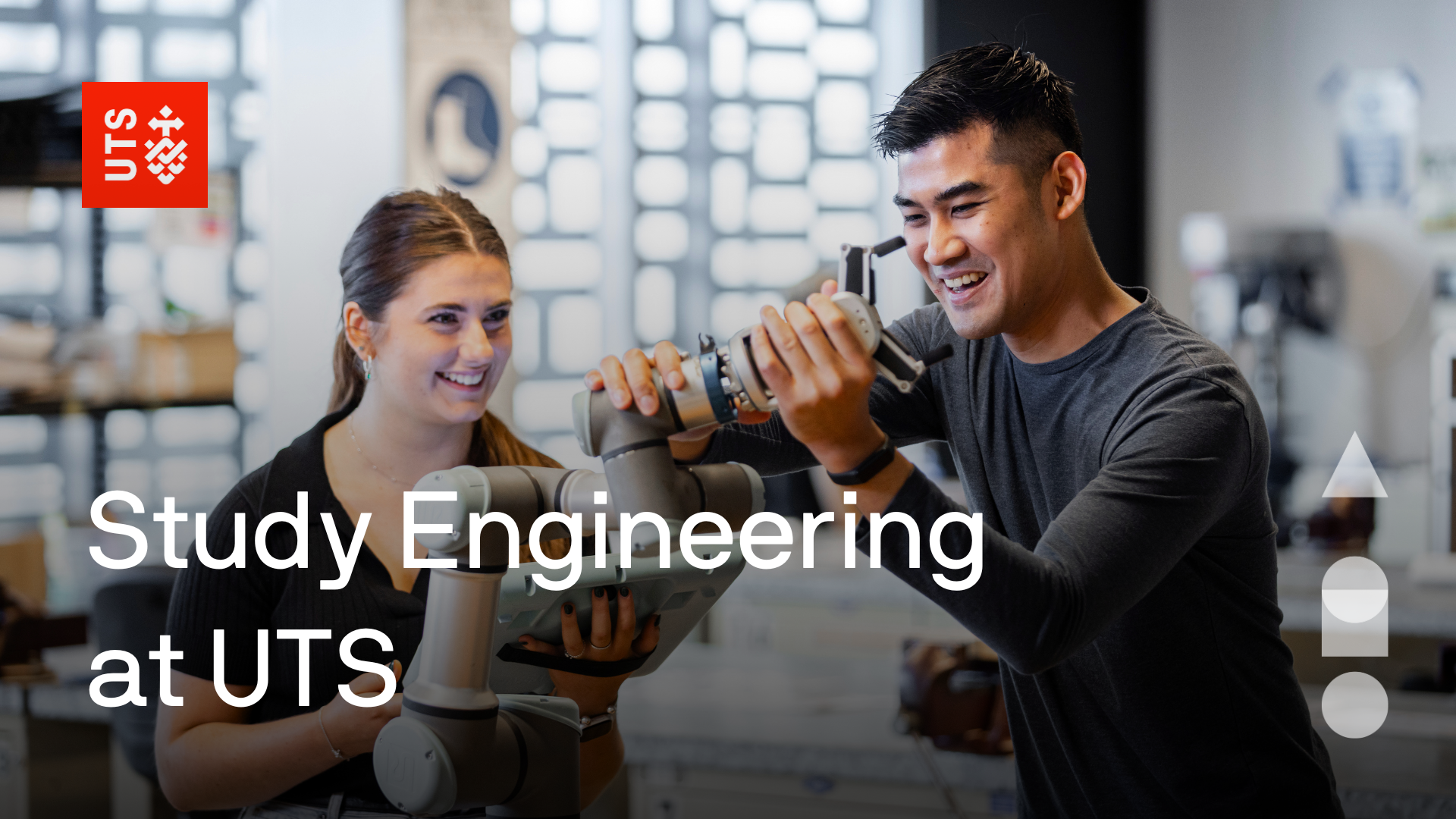 Male and female student holding a robotics arm