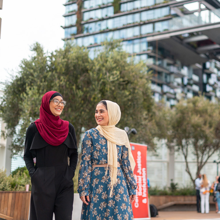 Two female UTS Humanitarian Scholarship students walking and smiling on the UTS campus.