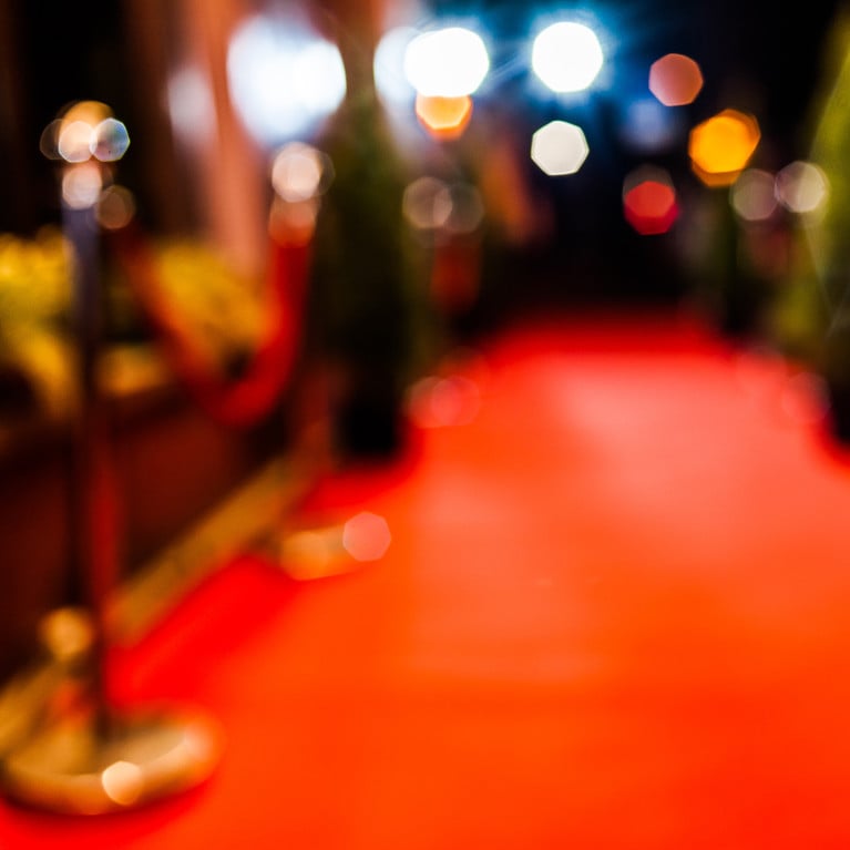 Blurry image of an empty red carpet entrance before an awards opening ceremony.