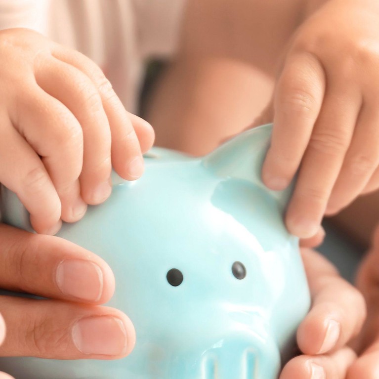 Child and parents hands holding a piggy bank