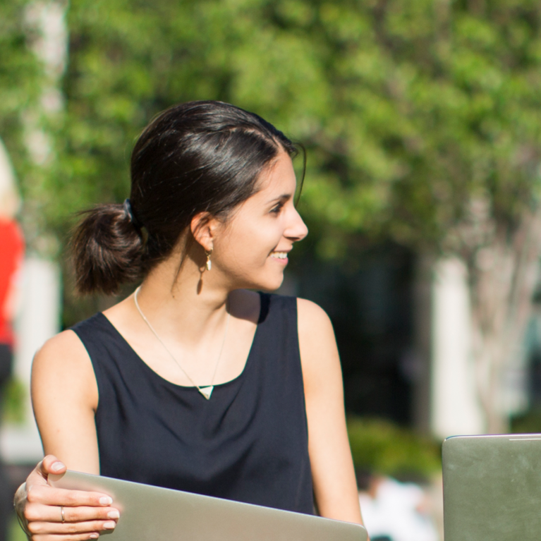 Two female students with laptops on the UTS Alumni green