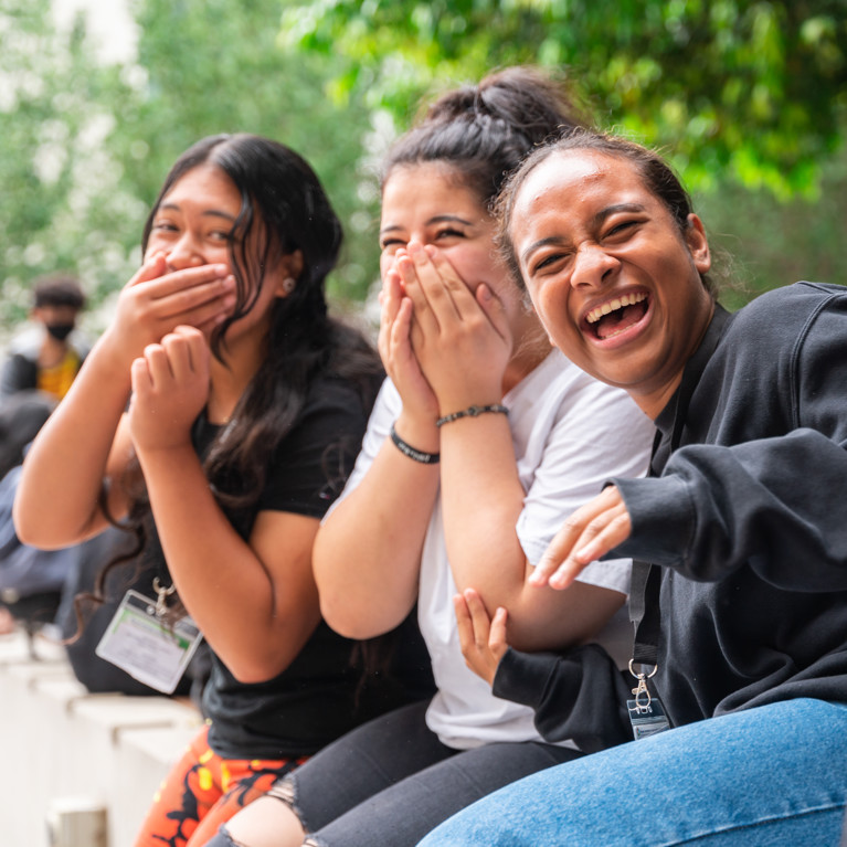 Three female high school students laughing.