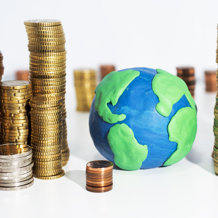 Stacked coins next to clay model of Earth.