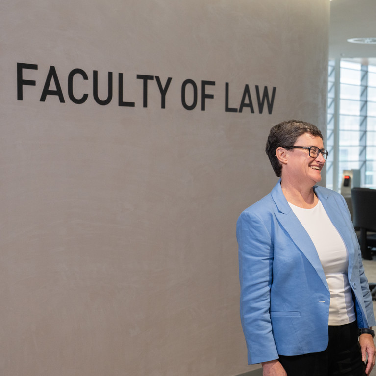 A Law professor and student meet at the Faculty of Law entrance on level 16. The Faculty of Law sign is shown behind them