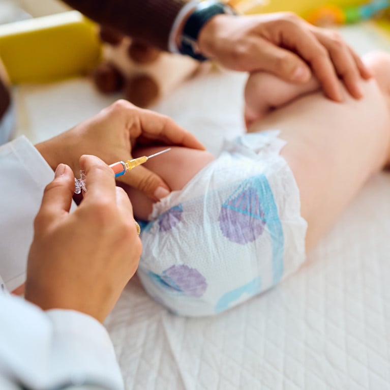 An image of a baby being administered a vaccine by needle