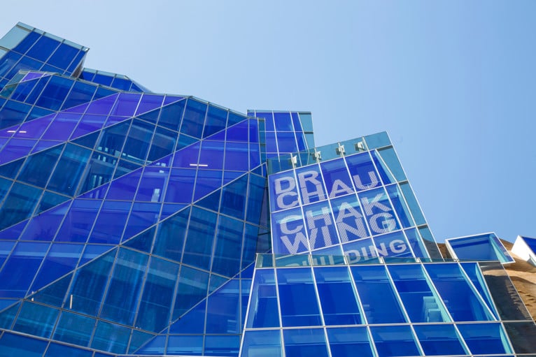 Architectural view of the UTS Chau Chak Wing Building featuring angular blue glass panels and large signage displaying the building’s name.