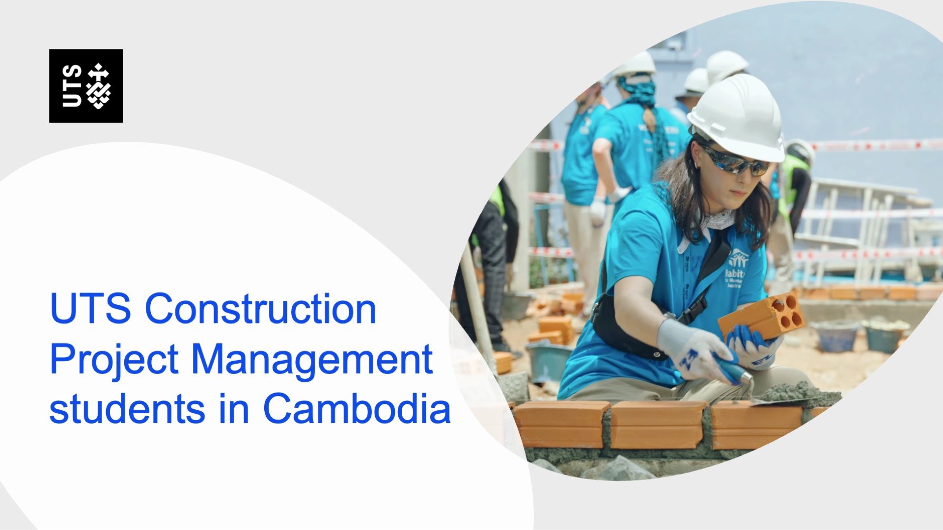 UTS students in protective gear and blue shirts lay bricks at a construction site in Cambodia, emphasizing teamwork and hands-on learning.