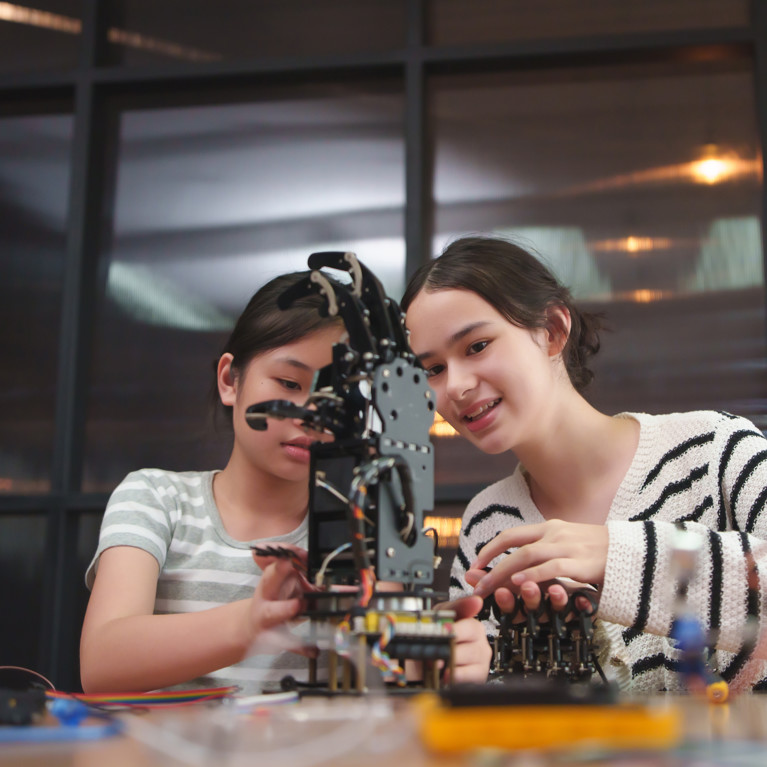 Two young girls interacting with a robot.