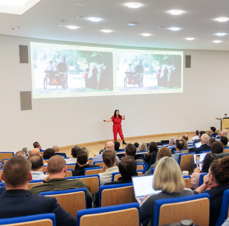 Shuya Gong standing at the front of the Chau Auditorium speaking at the CEO Summit