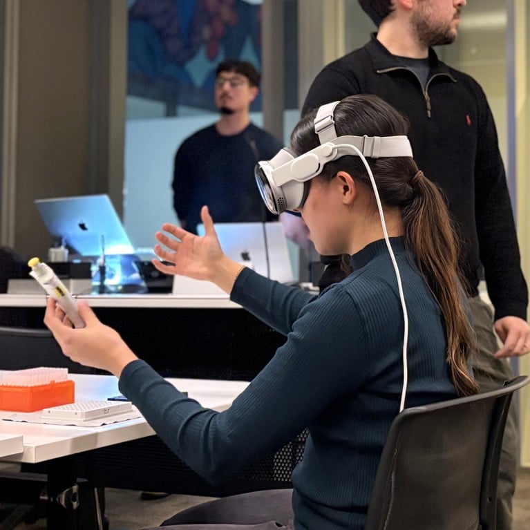 A man and woman seated in a conference room, using a virtual reality headset to experience a digital environment together.