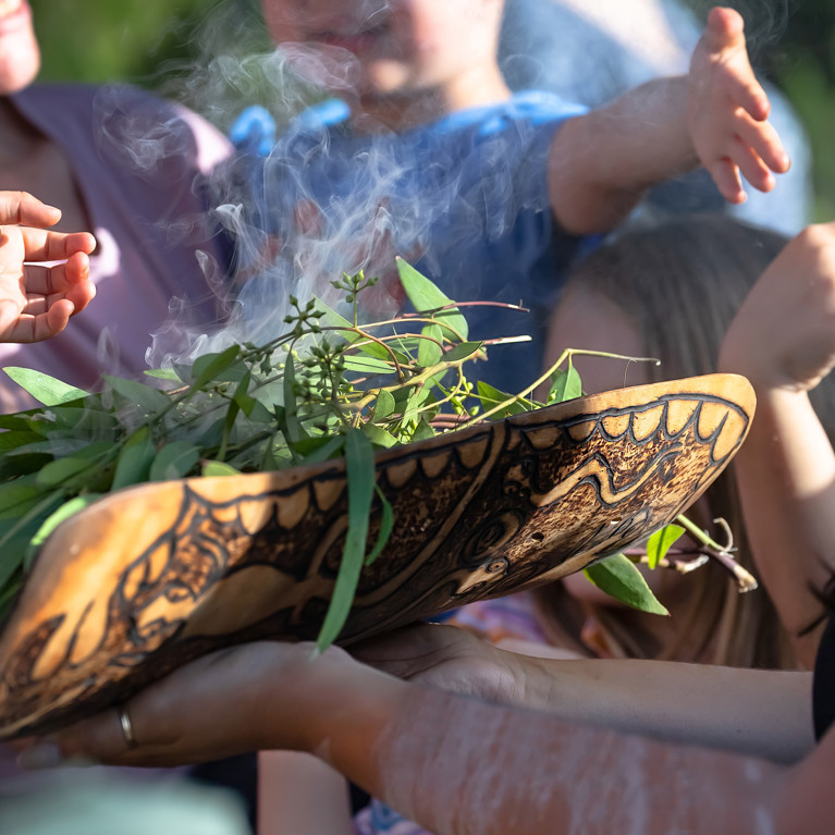 Australian Aboriginal smoking ceremony, human hands are touching the smoke of burning eucalyptus branches, the ritual rite at the community event, symbol of joining to the indigenous culture. Picture: Elena Pochesneva/Adobe Stock