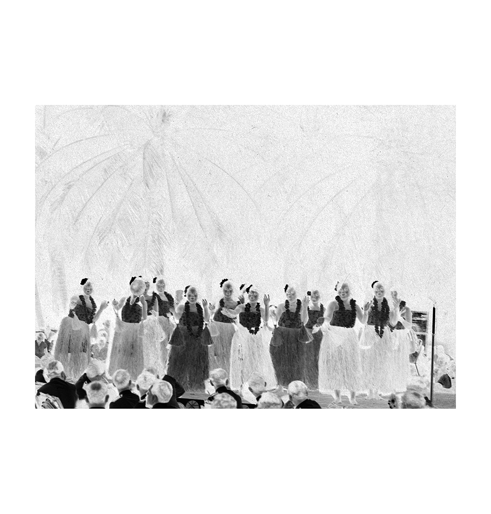 A close up of a negative of one of the historic photographs of Nauru showing a group of women performing a dance in front of a seated audience.