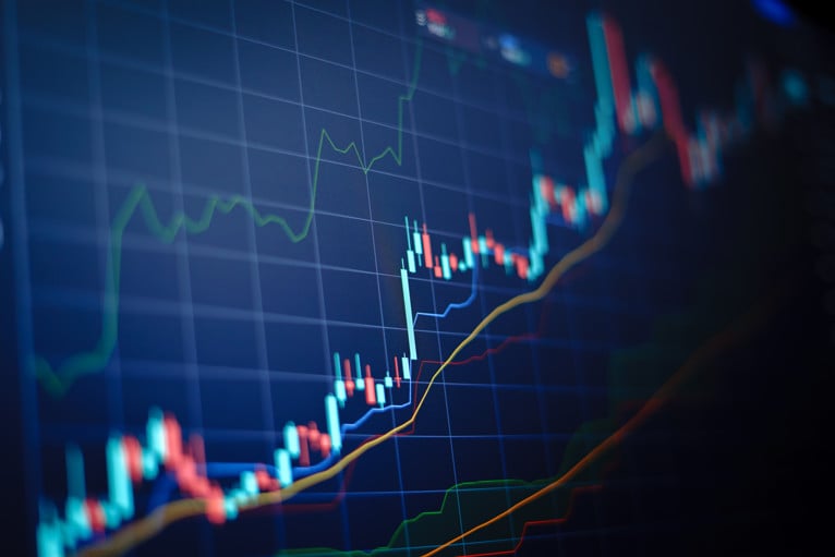 Closeup financial chart with uptrend line candlestick graph in stock market on blue colour monitor background.
