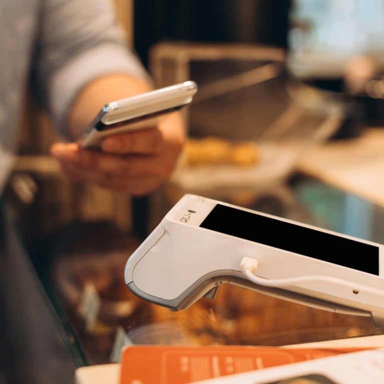 Customer paying contactless with mobile phone at pos terminal. Picture: Maria Vitkovska/Adobe Stock