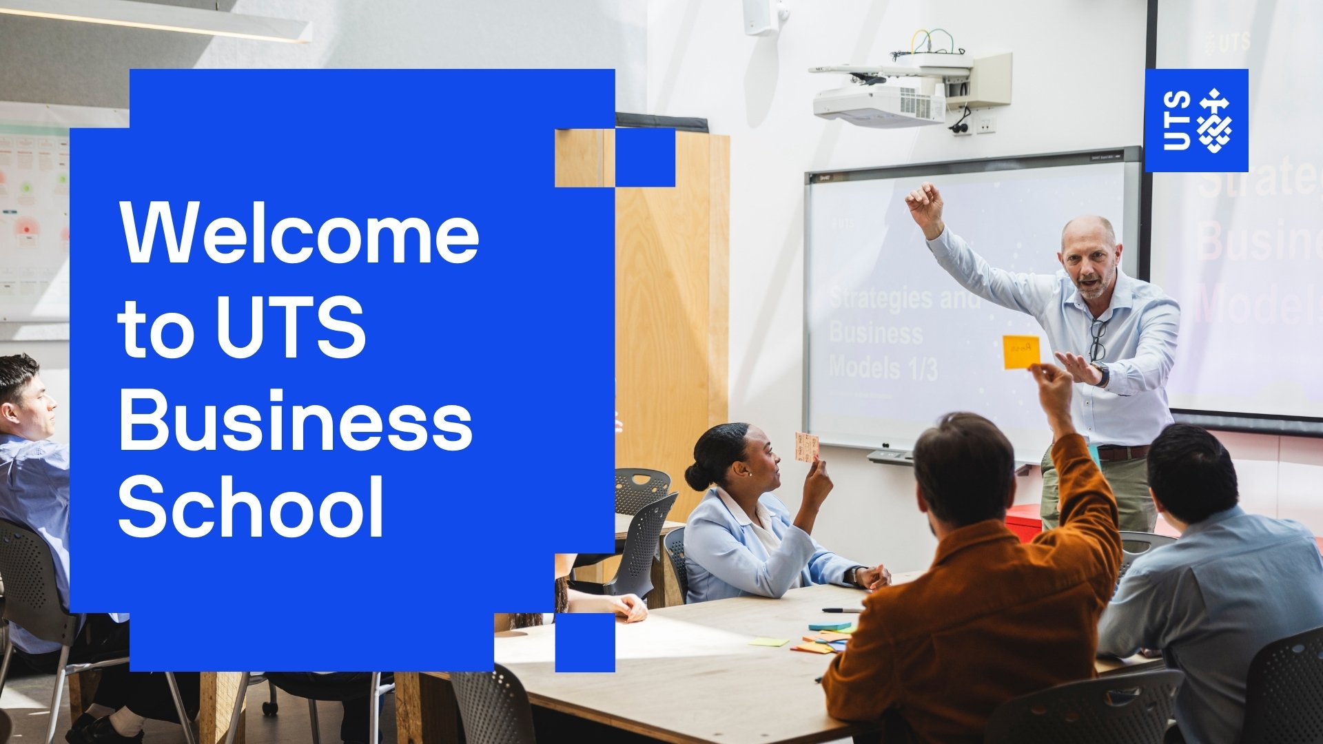 Left of screen, a large blue graphic reads Welcome to UTS Business School. On the right-hand side of the screen, it shows a brightly lit interior classroom with four students seated facing a male lecturer who is gesturing for them to hold up a post-it note.