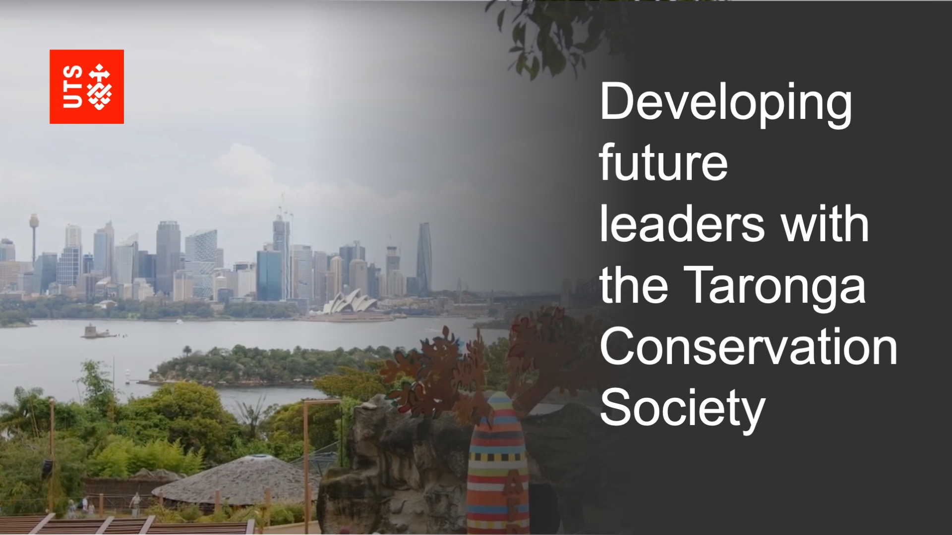 Skyline view of Sydney harbour. In the foreground, lush greenery surrounds structures. Text reads: "Developing future leaders with the Taronga Conservation Society" alongside a university logo.