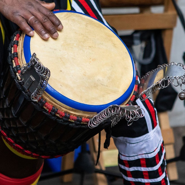 Closeup of three artist performing traditional colorful string wrapped african djembe drums while standing on stage during event