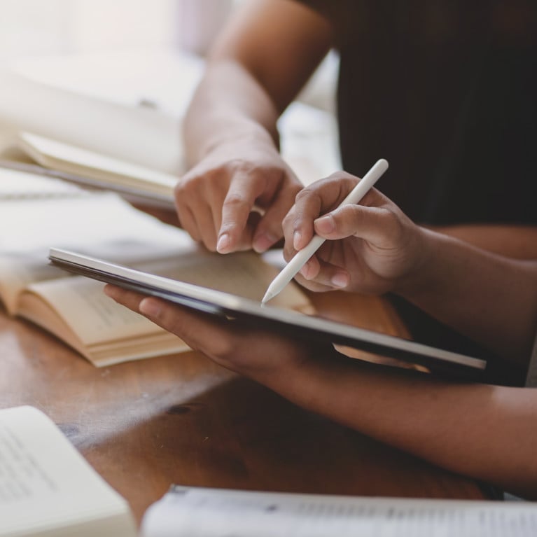 Closeup of two people studying together using books and electronic devices. Picture: Adobe Stock