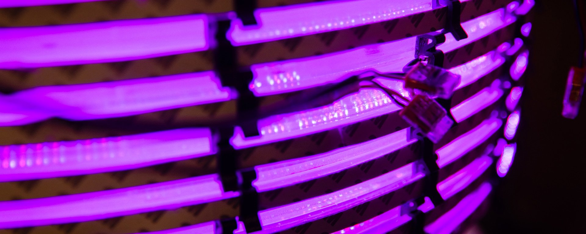 Purple LED lights arranged in horizontal rows create a glowing, futuristic pattern against a dark background. The mood is vibrant and modern.