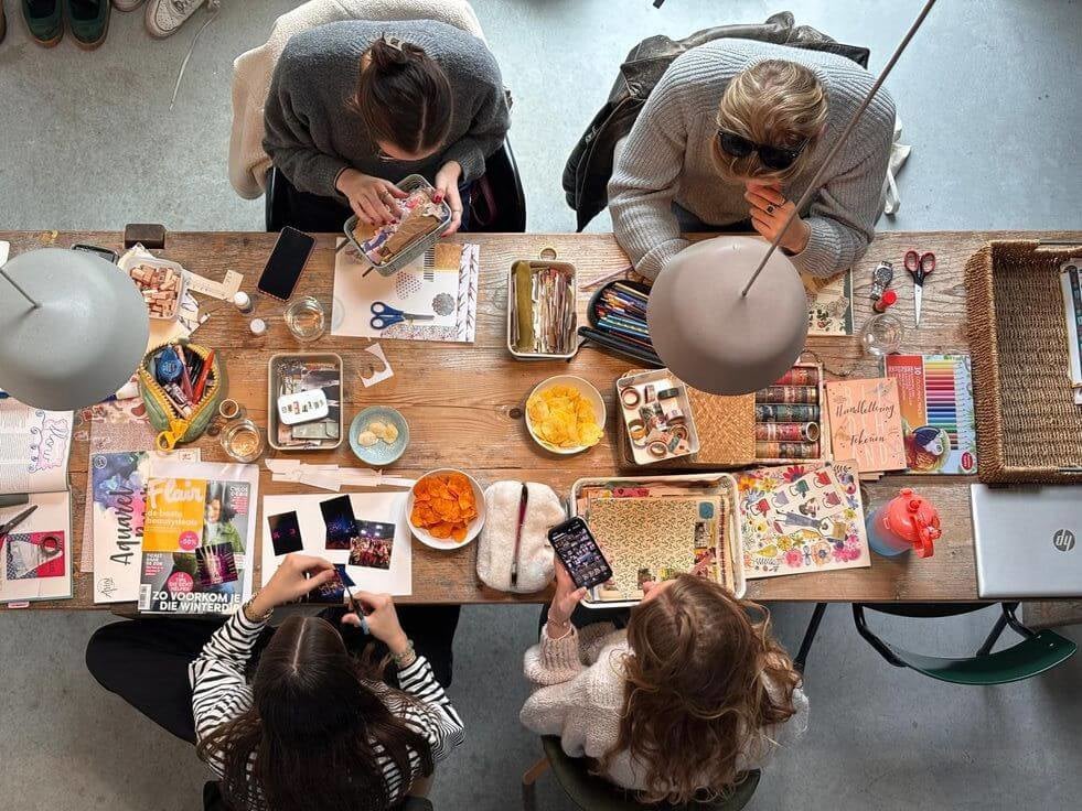 Four people sitting at a table scrapbooking