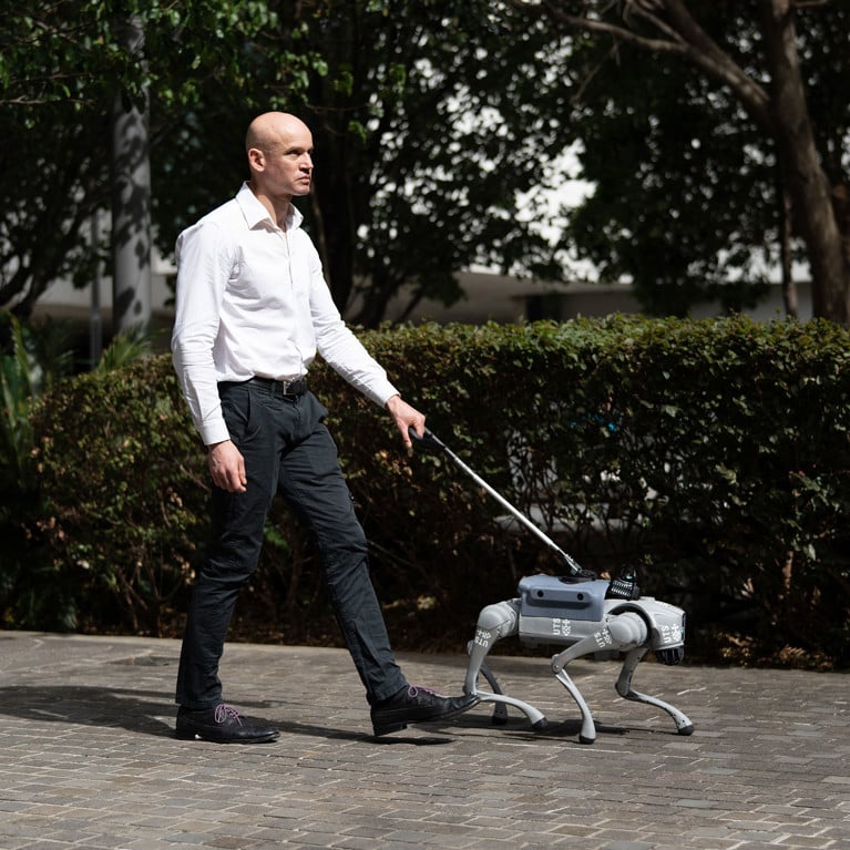 A man walks with a robotic guide through the city campus of University of Technology Sydney.