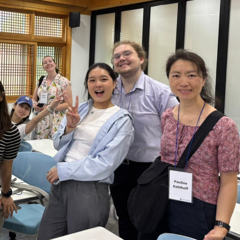 Bella with a group of other students and teachers smiling at the camera.