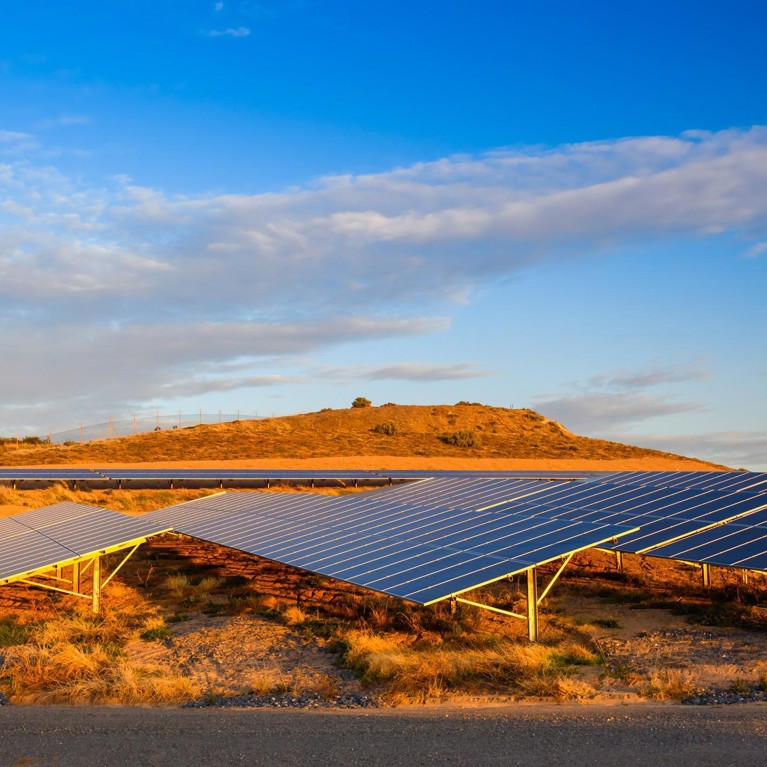 Solar panels in the foreground with a bright blue sky