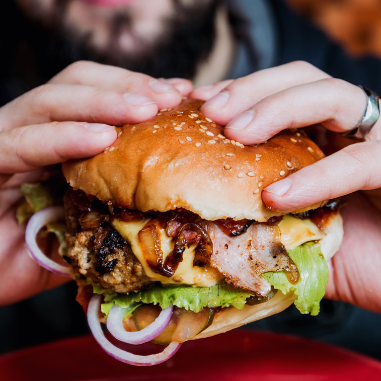 Young man eating a cheeseburger.
By romaset Adobe Stock