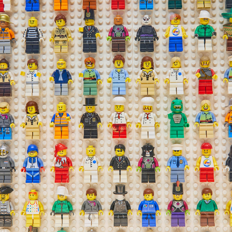 Little Lego people in many costumes lined up on a Lego wall. Picture: Jill Greer. Adobe Stock