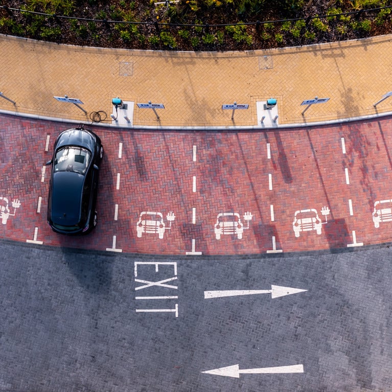An aerial view of an electric vehicle charging station with an electric car charging in a parking space. Picture: Teamjackson/Adobe Stock