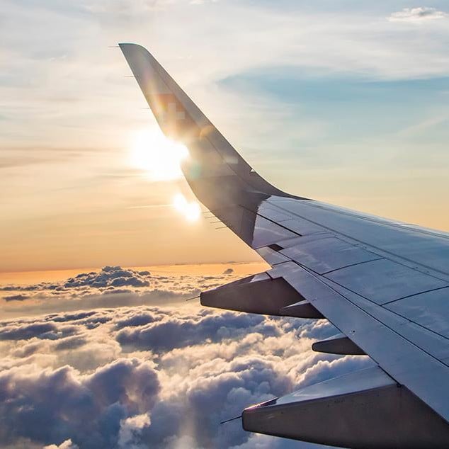 Image of a wing of a plane and the sun, shot through the window