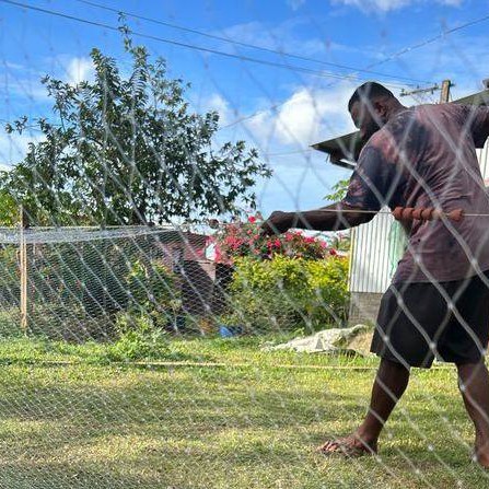 A Fijian man is fixing a fishing net