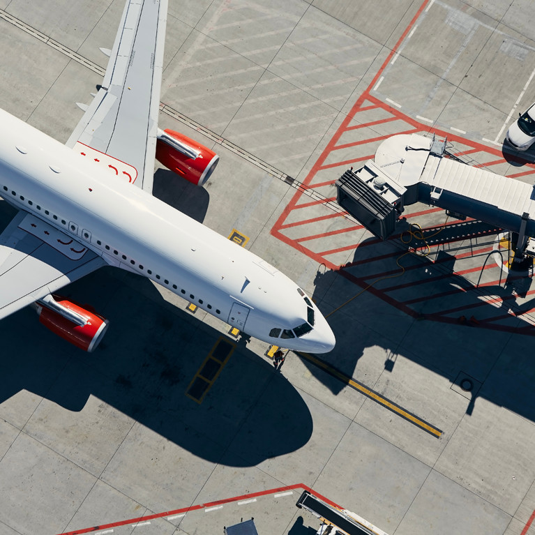 Aerial view of a plane. The aeroplane is in front of Apassenger boarding bridge from the airport terminal.