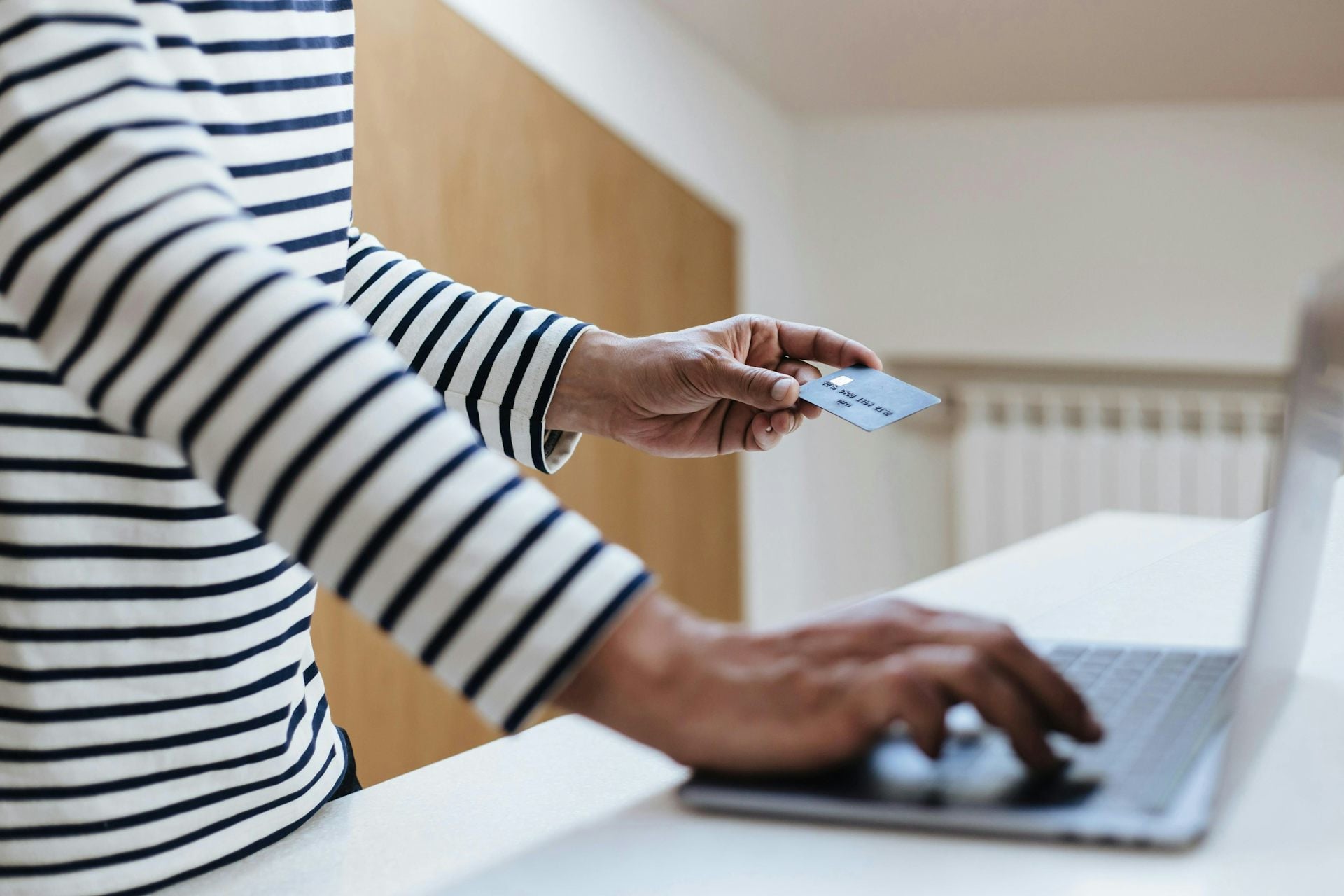 Closeup of a person holding a credit card while working on a laptop: Picture: Ron Lach/Pexels