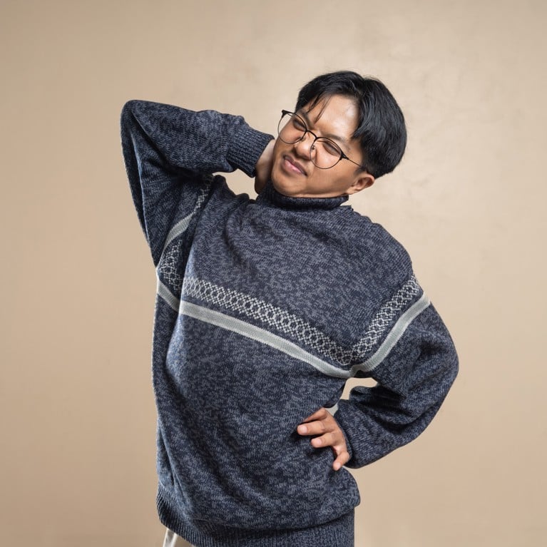 Asian man wearing eyeglasses and sweater stretching indoors, feeling body pain. Picture: Dany Kurniawan/Pexels