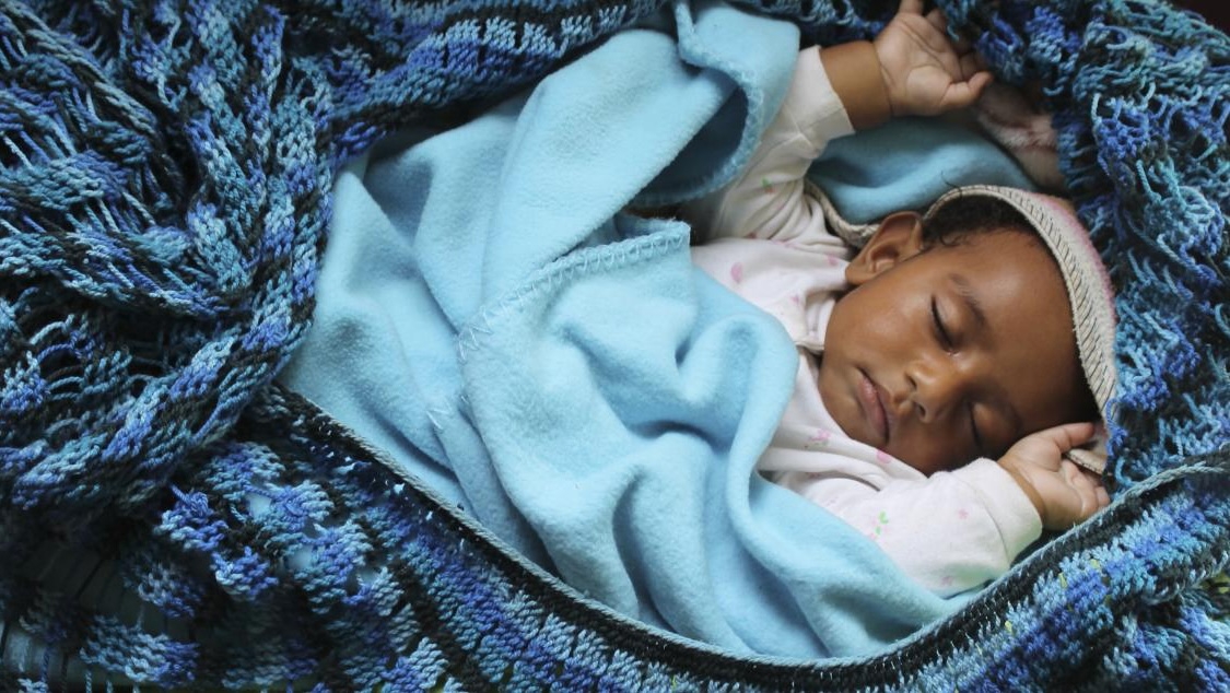 sleeping baby swaddled in blue blankets