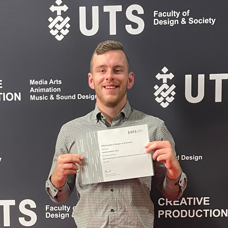 UTS student Aaron King smiling and holding a certificate.