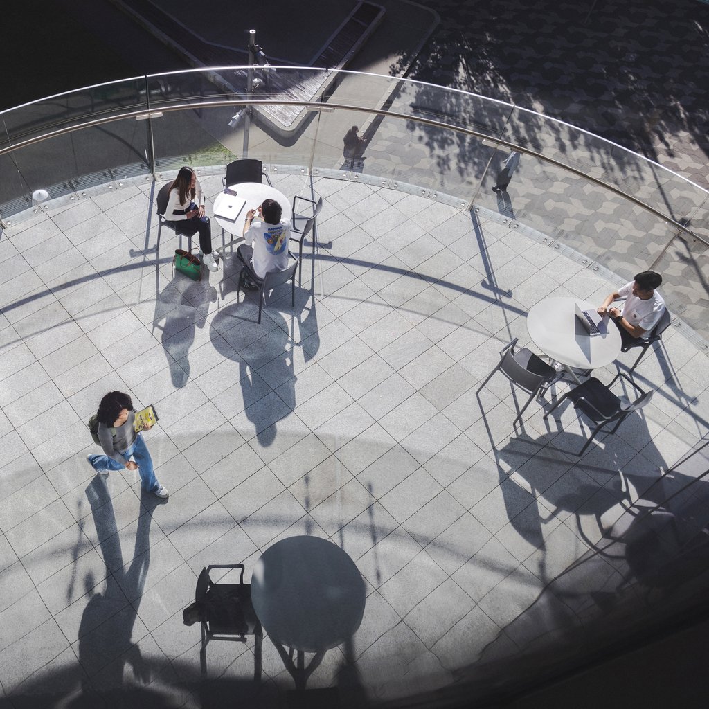 Aerial view of students sitting at tables on outdoor balcony of UTS Library.