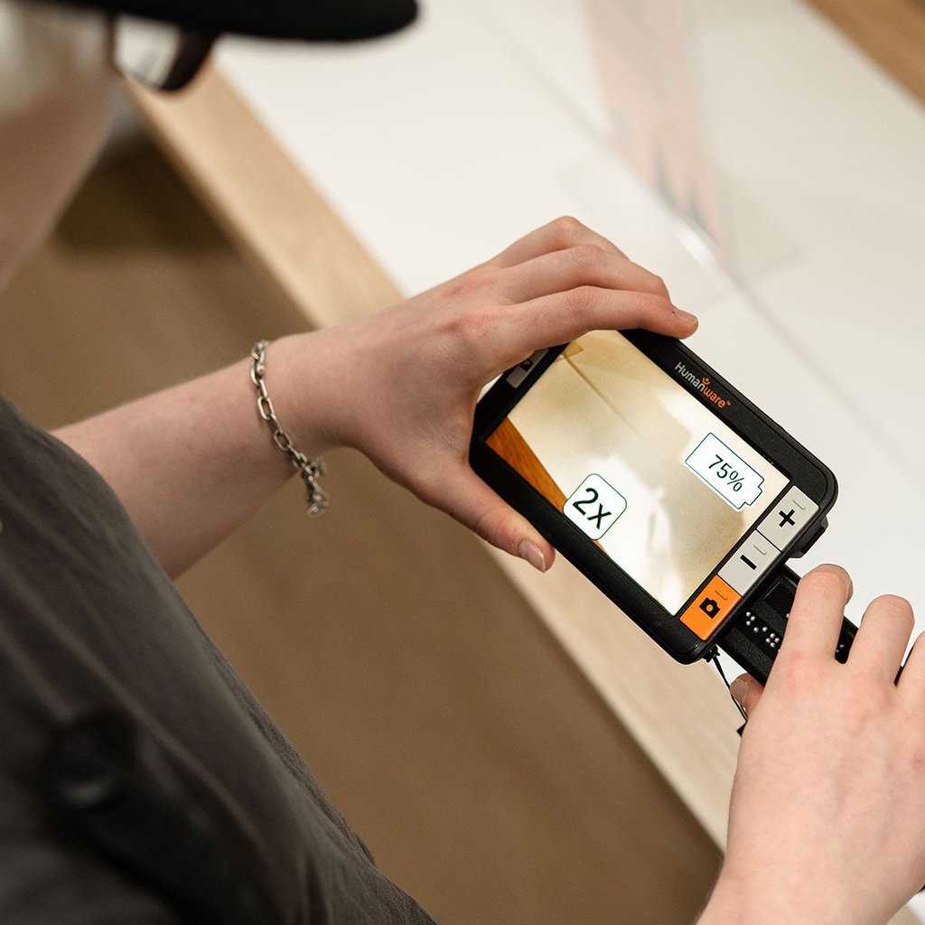 A person uses an electronic device to scan their environment and magnify details for easier visibility.