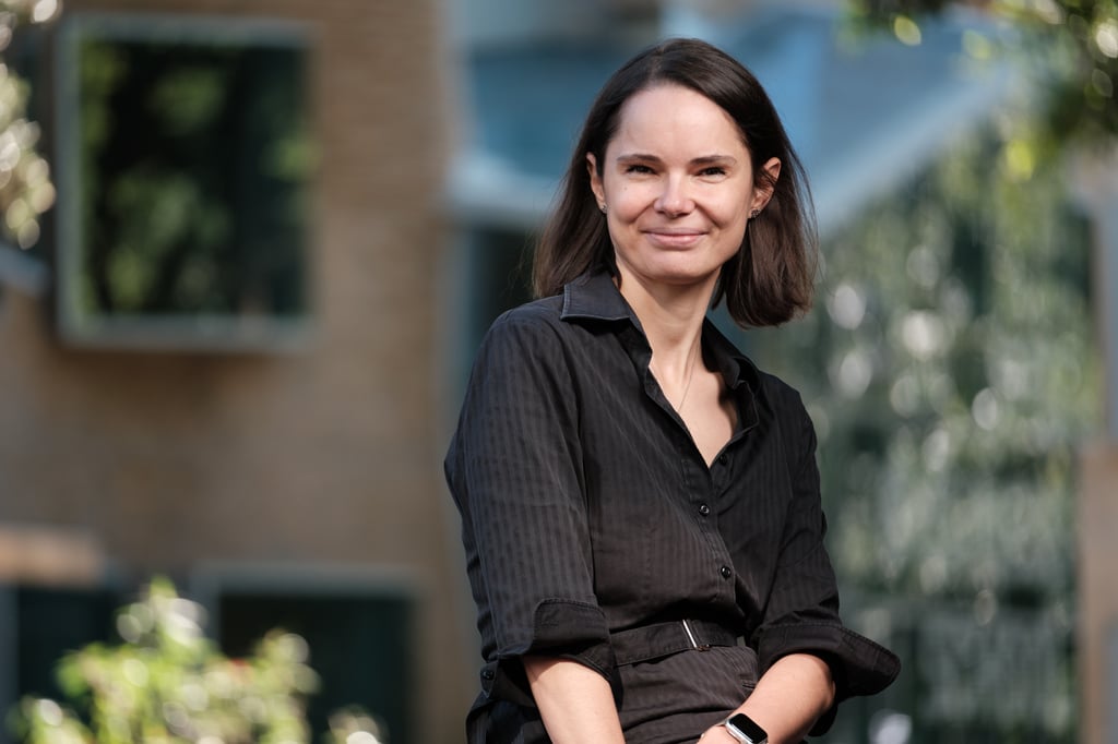 Pavlina sits in front of the UTS Business School. She's wearing a black shirt and smiling at the viewer.