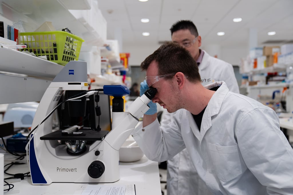 Man in research facility looking through microscope