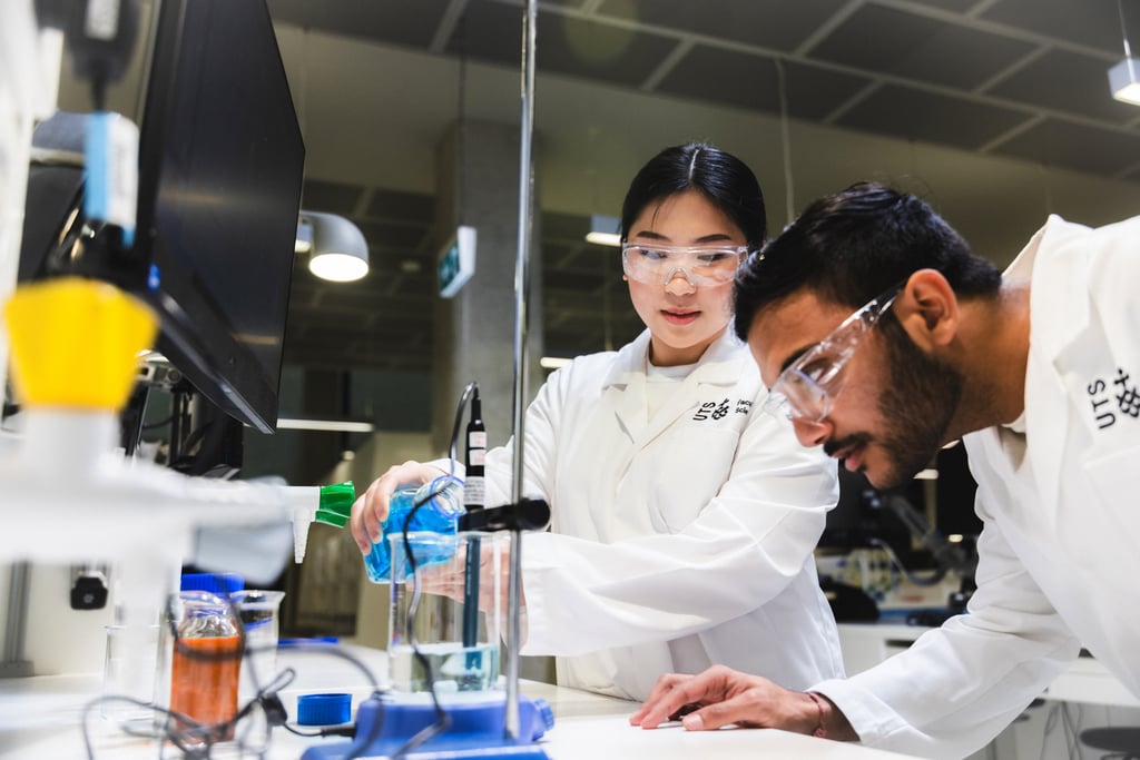 Female and male students in white lab coats working on science demonstration in UTS Super Lab.