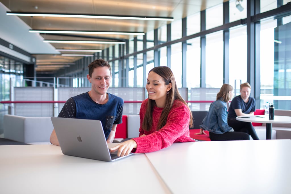 Two University of Technology Sydney students working on a laptop together.