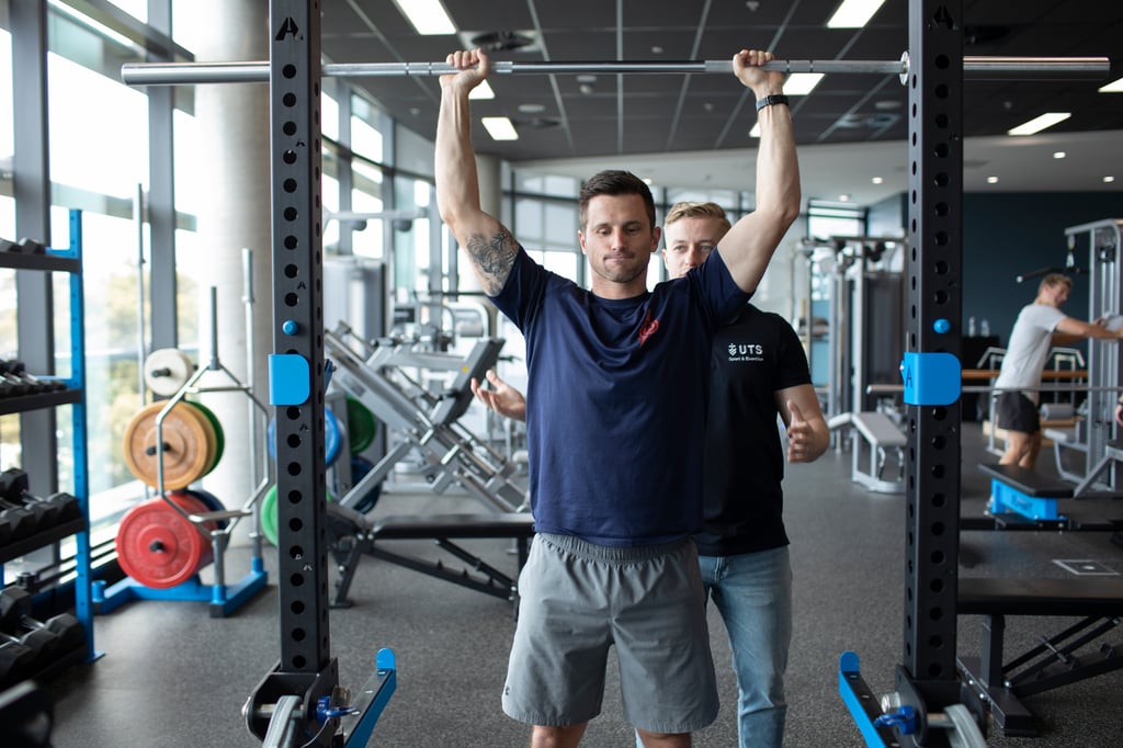 Man lifting weights under the instruction of a supervisor