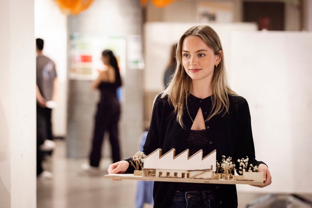 An architecture student holding a 3D model.