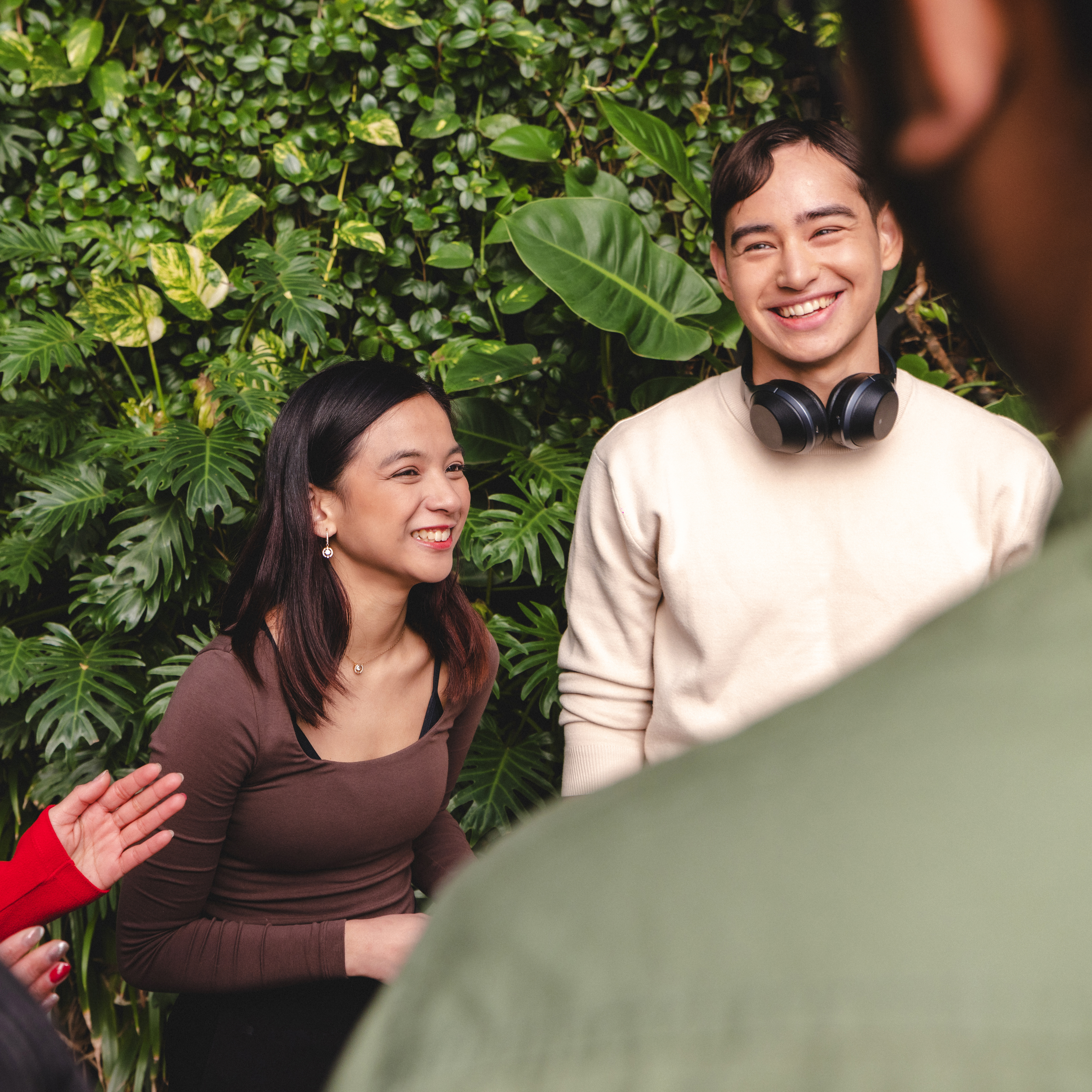 Male and female students standing in front of the green wall near the Engineering and IT building.
