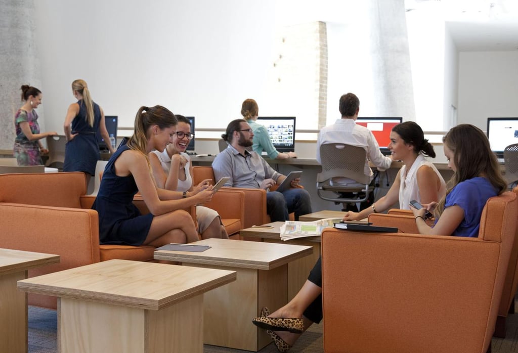 A group of people sitting at different tables in a bright, airy space.