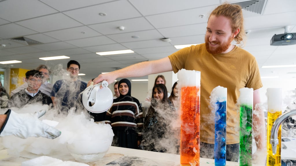 Male student using beakers with coloured liquid in a science class.