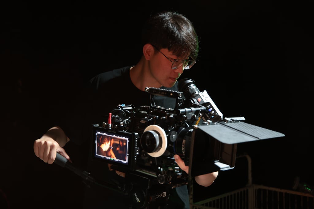 Student looking into ARRI camera in dark studio space.